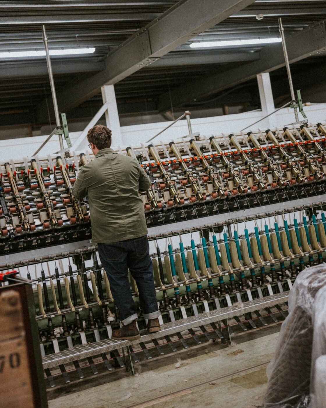 A member of the team at a spinning frame, colourful bobbins in view