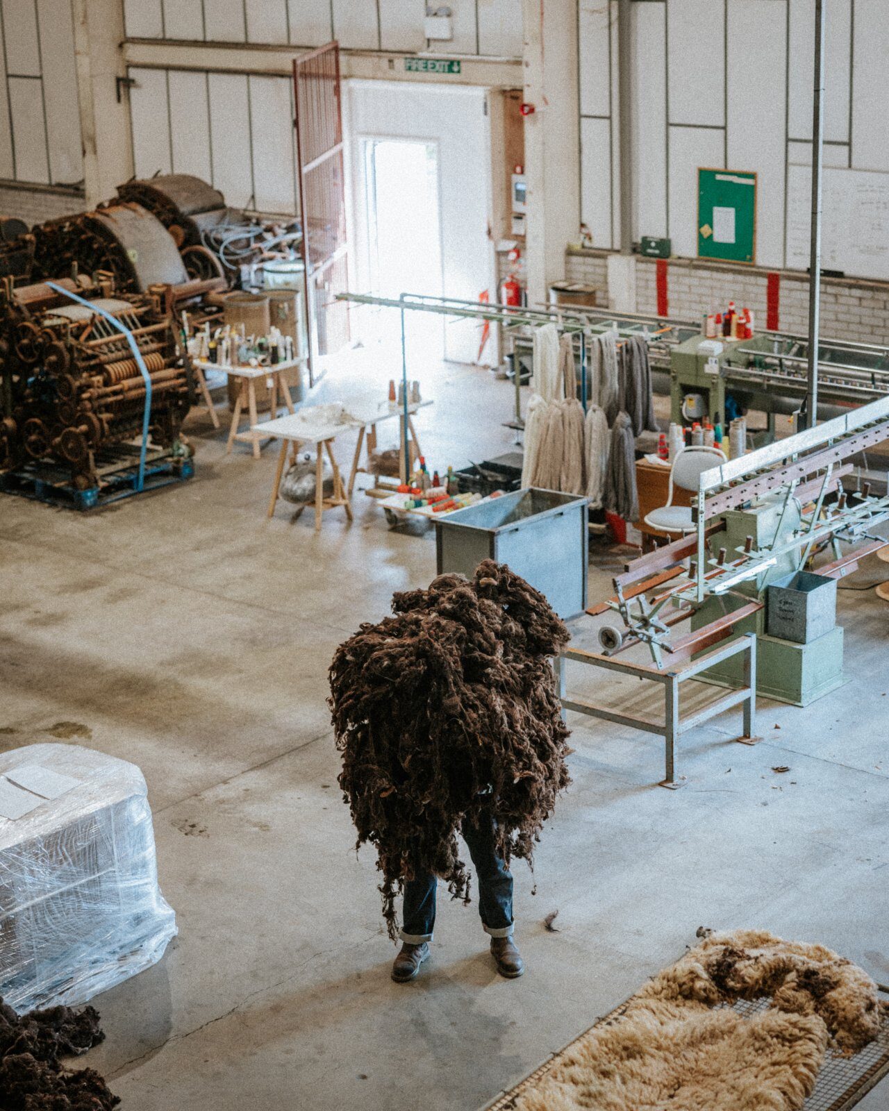 Elevated view of the mill floor, with heritage spinning machinery, a forklift and raw fleece being carried across the room