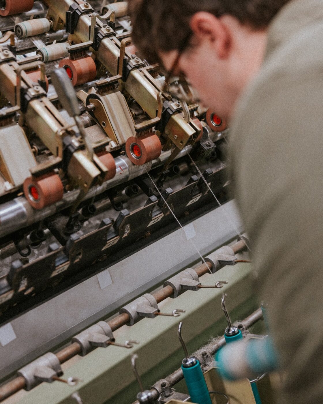 Close detail of a hand adjusting the rollers on a spinning frame